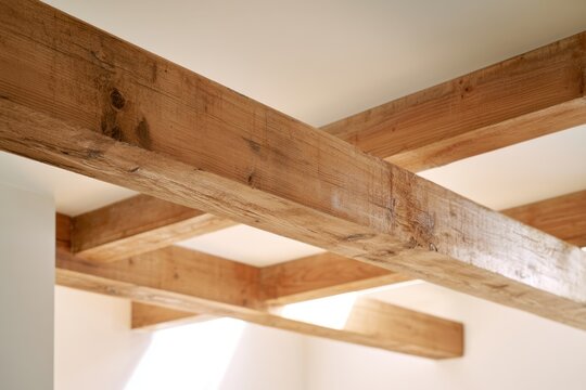 Rustic wooden ceiling beams crossing each other in a bright modern interior space with natural light filling the room