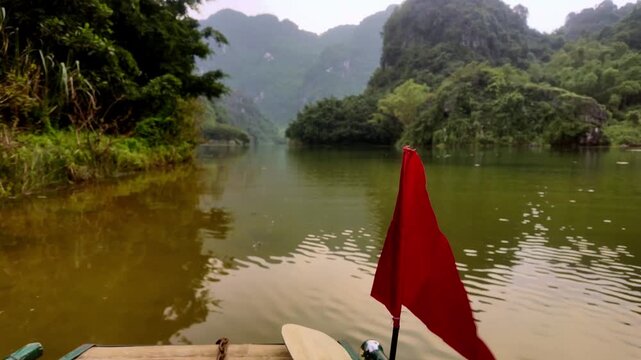 Wooden Boat Cruise with Red Flag Navigating Misty Trang An River in Ninh Binh Vietnam - Point of View Stabilized Gimbal Shot Color Graded B-Roll