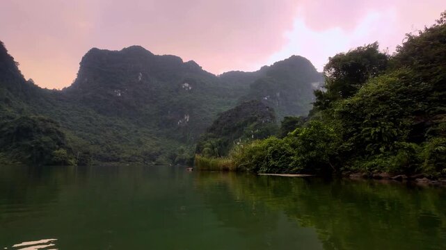 Serene Sunset Boat Glide Across Tranquil Trang An River Surrounded by Limestone Karsts in Ninh Binh Vietnam - Stabilized Color Graded B-Roll
