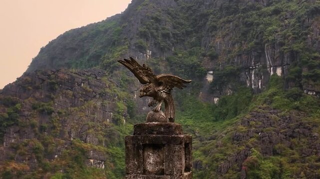 Majestic Eagle Statue Perched at Hang Mua Viewpoint in Ninh Binh Vietnam surrounded by Misty Karst Peaks at Sunset
