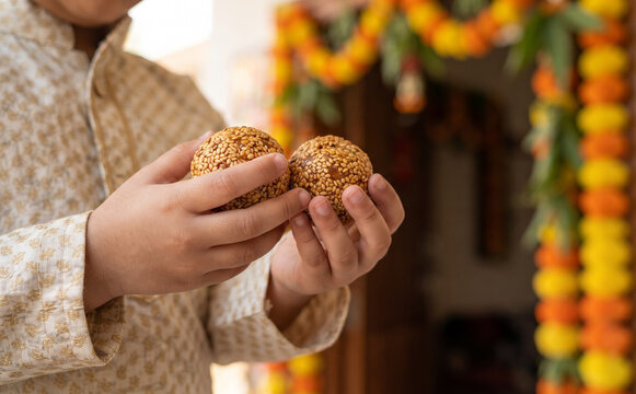 Young Indian boy holding sweet tilgul lundoo balls during traditional festival celebration