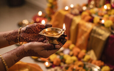 Obraz premium Woman with henna on hands holding a lit oil lamp for celebration