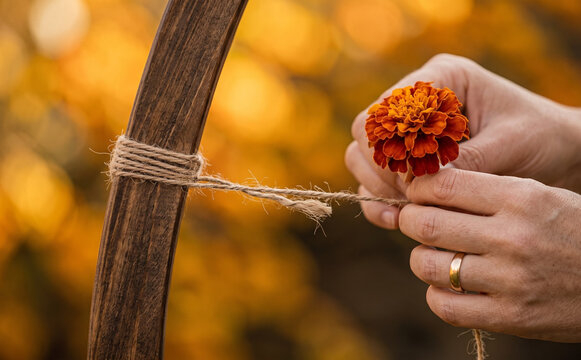 Crafting floral autumn decor with marigold flower and twine tied around a wooden arch