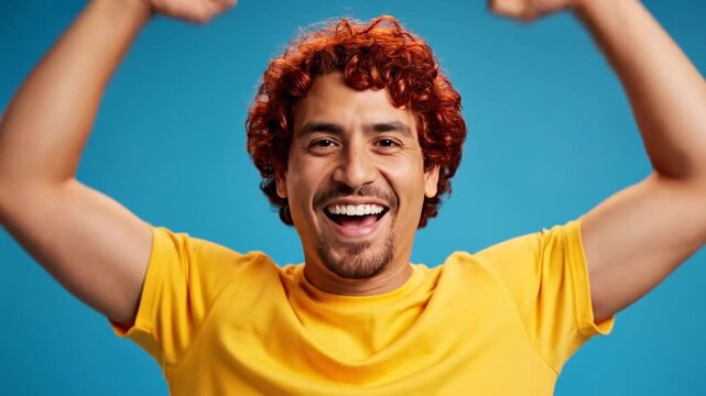 A happy young man celebrates with his arms raised high up