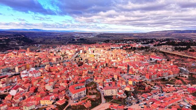 Morning light over Teruel municipality, Spain. Aerial view of sprawling European townscape under bright patchy clouds and sunlight.