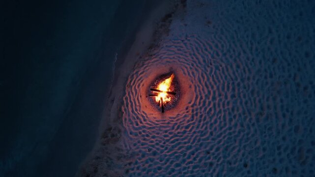 Aerial view of a glowing campfire sandy beach at night
