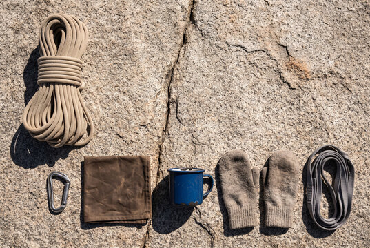 Climbing gear flat lay on granite rock with rope and carabiner