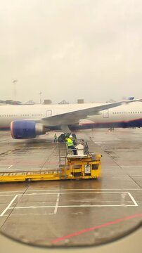 Large passenger airplane parked on rainy airport tarmac ready for boarding