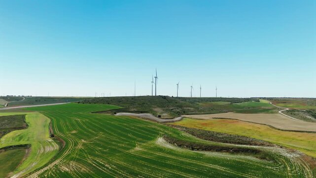 Drone approach to wind turbines above rolling farmland in Avila