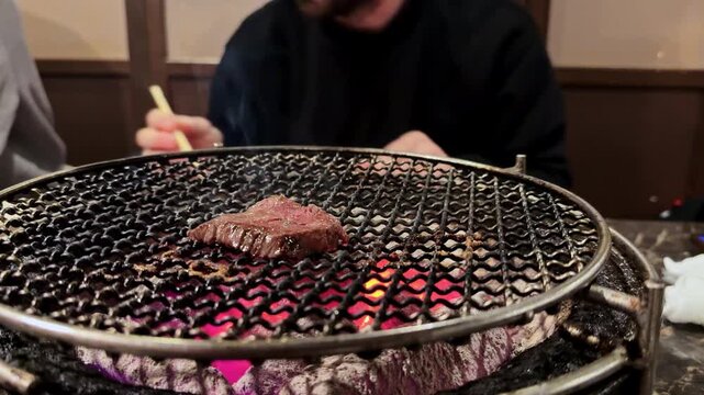 Person grilling yakiniku beef on a traditional Japanese barbecue