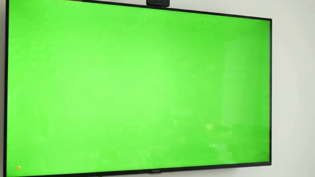 Large wall-mounted smart tv with green screen display for custom compositing and digital signage mockup