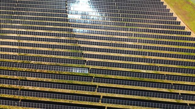 Sunlight glinting on solar panel rows at a solar farm in Avila