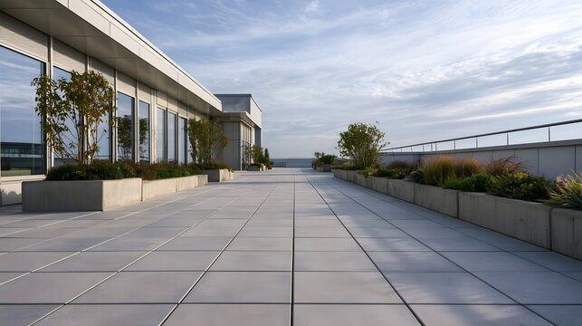 Modern rooftop walkway with concrete planters  glass facade  and clear sky overhead in minimalist architectural design