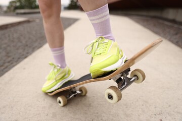 Woman riding skateboard on city street, closeup © New Africa