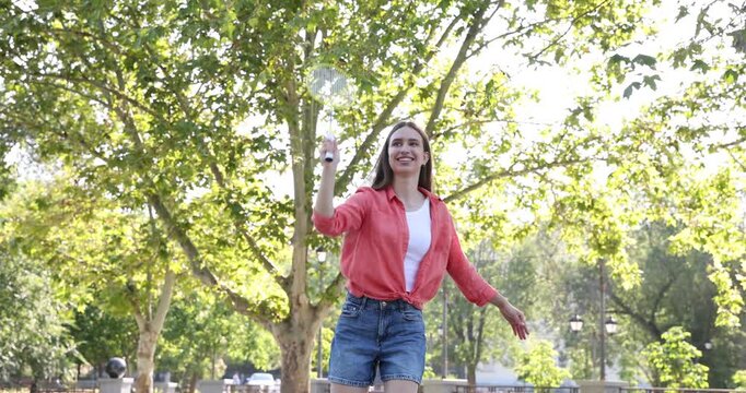 Happy teenage girls with rackets and shuttlecock playing badminton outdoors