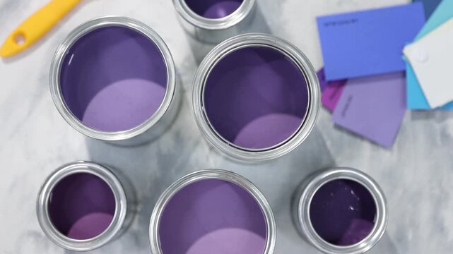 Cans with paint in shades of purple and color palettes on textured table, flat lay