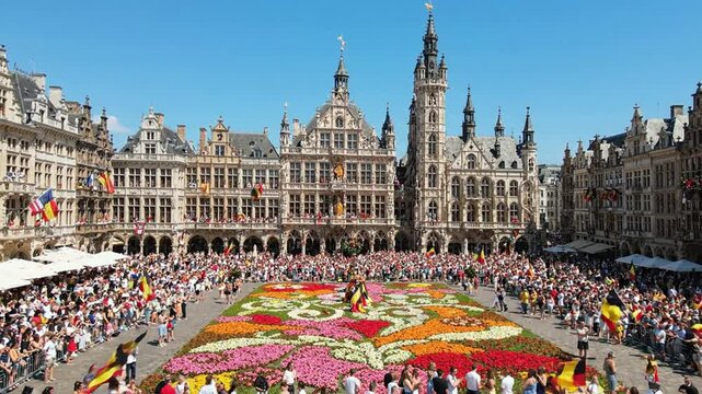 Grand place brussels flower carpet festival with waving belgian flag and crowds belgium grote markt