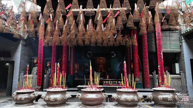 Smoke rising from traditional incense sticks in an ornate burner surrounded by hanging spiral incense coils in a historic Chinese temple, Cholon, District 5, Ho Chi Minh City, Vietnam