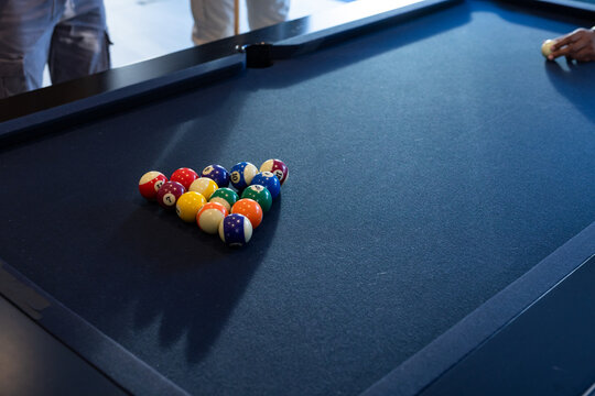 Male players positioning cue ball while preparing break on blue-felt pool table with racked balls