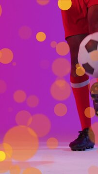 Animation of lens flares over low section of african american player dribbling soccer ball