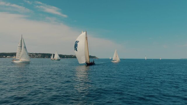 Fast drone tilt up revealing classic yacht racing under spinnaker