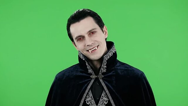 Halloween vampire man posing with fangs on green screen