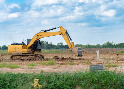 Heavy-duty excavator machinery excavating dirt at a land development construction site before building foundation works.