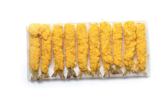 flat lay view of uncooked breaded Ebi Furai prawns lined up in a transparent plastic tray isolated on a white background.