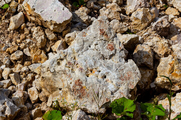 Rugged texture of white limestone boulders and crushed rocks scattered across a sunlit quarry, showcasing natural geological formations and raw stone patterns in an open excavation site © PhotoChur