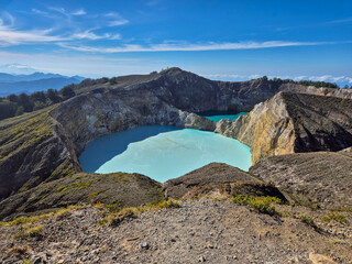 Stunning turquoise crater lakes of Mount Kelimutu under a clear blue sky in Ende, Flores, Indonesia. © egar