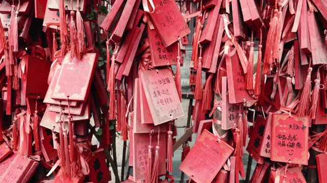 Close-up of red wish ribbons and handwritten blessing plaques displayed at a traditional religious site in Tianjin, China.