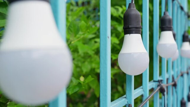 Hanging white LED light bulbs string on light blue fence