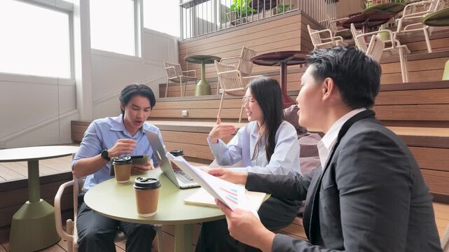 Asian Business Professionals Discussing Data in Modern Bangkok Coworking Space