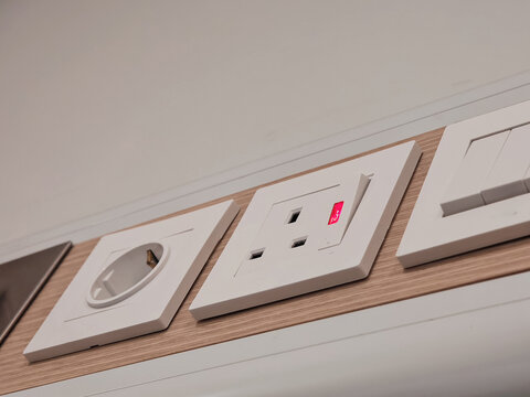 modern white electrical wall sockets installed on a warm wood panel, showing household power outlets, electrical connection points, interior architecture, and modern home electrical design.