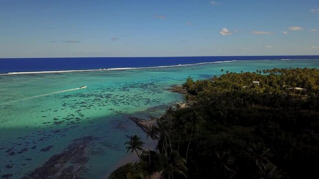 Aerial drone view over tropical island coast with clear blue lagoon and coral reefs.