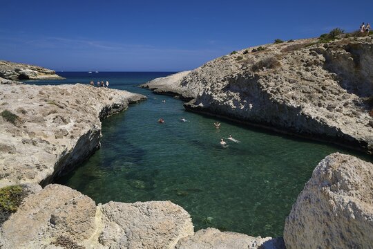 Swimmers enjoy turquoise water between rocky cliffs under clear blue sky, Kapras, Kapros, Beach, Kapros Beach, Caves, Paralia Kapros, Milos, Cyclades, Greek Islands, Greece