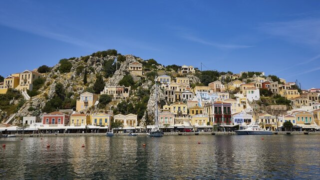 Charming coastal town with colourful buildings, calm waters and mountains in the background, Symi Town, Symi, Dodecanese, Greek Islands, Greece