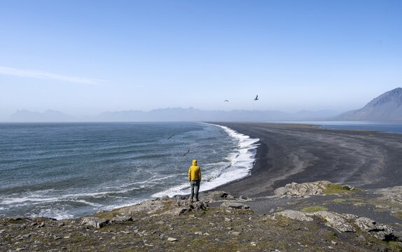 Tourist looking over long black sand beach, Reynisfjara Beach, South Iceland, Iceland