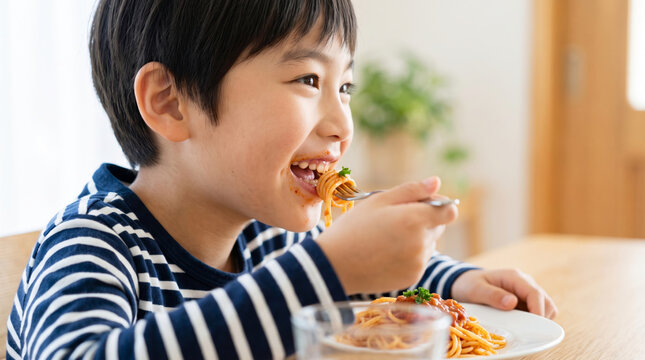 笑顔でスパゲッティを美味しそうに食べる男の子の食事風景