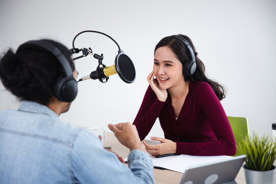 Asian woman interviewing man for podcast recording in studio with professional equipment