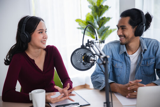 Happy Asian duo making a video podcast or streaming live from their home studio.