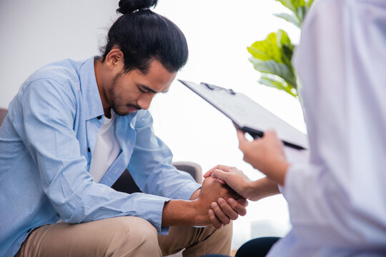 Stressed Asian man talking to doctor during mental health therapy session