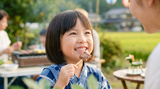 夏の屋外で焼き鳥を笑顔で食べる甚平姿の女の子