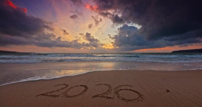 2026 Written Text in Sand on a Beach at Sunset With Dramatic Clouds and Ocean Waves