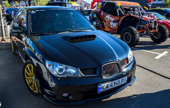 Glossy black Subaru Impreza WRX STI with iconic gold wheels, functional hood scoop, and aggressive styling, showcasing legendary JDM rally performance heritage