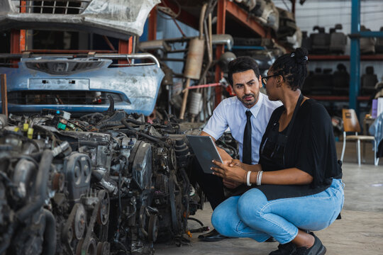Professional Asian doctor and Black female worker discussing inventory in auto parts warehouse