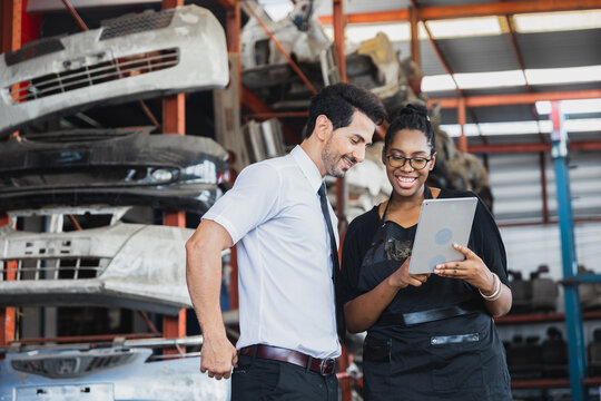 Diverse business partners using tablet to check auto parts in industrial warehouse storage