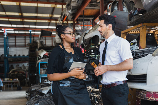 Professional Asian doctor and Black female worker discussing inventory in auto parts warehouse