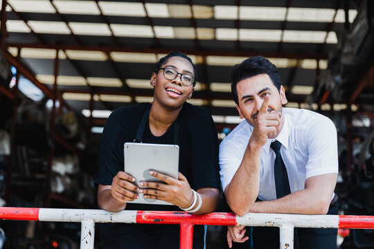 Diverse Asian doctor and Black female worker discussing inventory in industrial warehouse