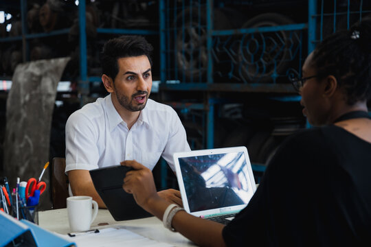 Surprised coworkers discussing project on tablet and laptop in modern office